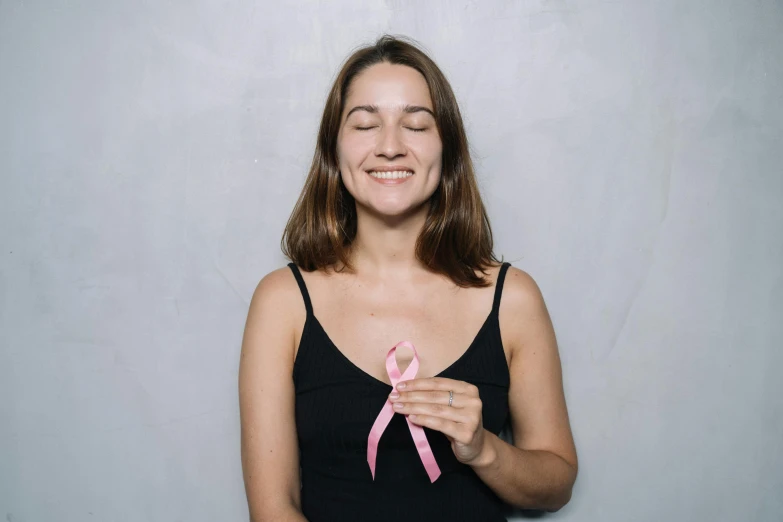 a woman with a pink ribbon on her chest, a photo, by Emma Andijewska, pexels contest winner, she is smiling, nanogirl, h3h3, small in size