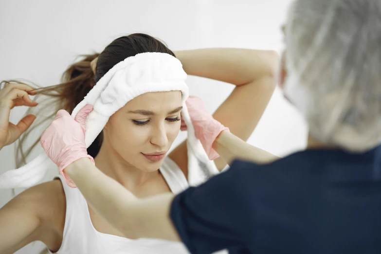 a woman drying her hair in front of a mirror, facial actuary, wearing a headband, in pain, profile image