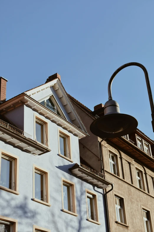 a clock that is on the side of a building, by Kristian Zahrtmann, unsplash, art nouveau, under street lamp, detmold charles maurice, light blue sky, square