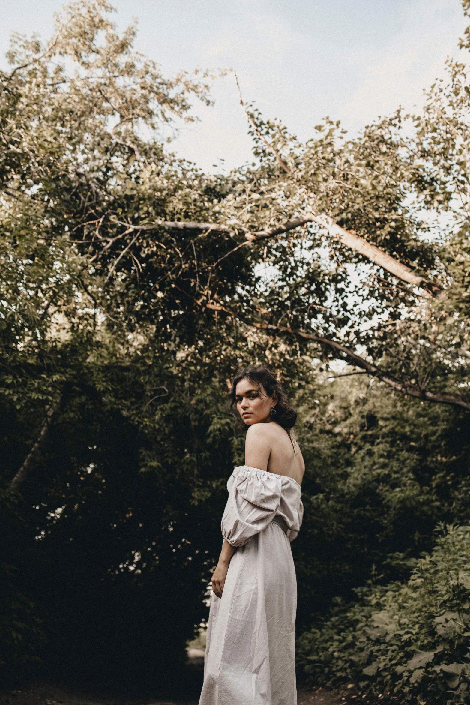 a woman in a white dress standing in a forest, inspired by Elsa Bleda, unsplash, renaissance, bare shoulders, grey, natural complexion, in a garden