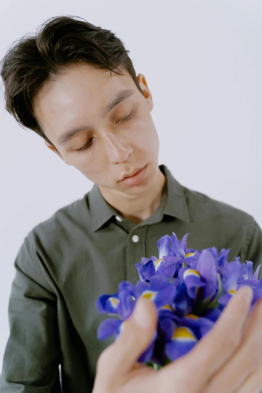 a man holding a bouquet of purple flowers, an album cover, inspired by Jean Malouel, kiko mizuhara, video still, ignant, focus on iris