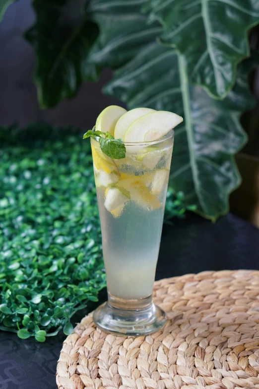 a glass of lemonade sitting on top of a table, apple, in style of lam manh, detailed product image, greens)