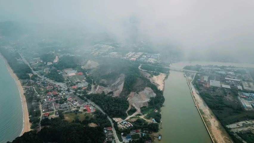 an aerial view of a large body of water, by Basuki Abdullah, pexels contest winner, rain and haze, building along a river, rock quarry location, small town surrounding