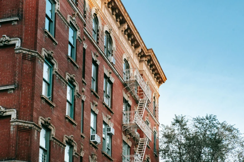 a tall brick building with a fire escape ladder, pexels contest winner, harlem renaissance, late summer evening, ornate carved architecture, conde nast traveler photo, exterior view