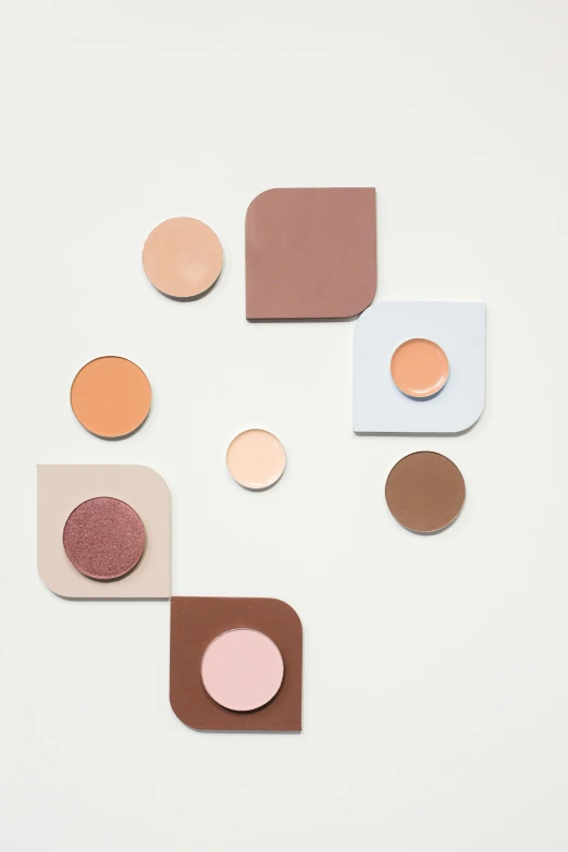 a group of different colored circles on a white surface, inspired by Bauhaus, trending on unsplash, brown and pink color scheme, square shapes, makeup, taupe