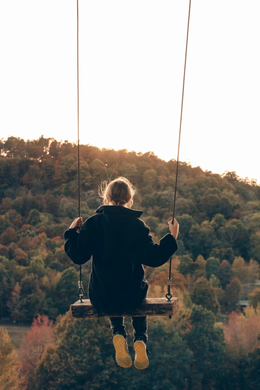 a person on a swing with trees in the background, trending on pexels, comforting, on a hill, autum, looking out