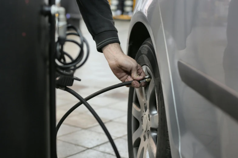 a person pumping gas into a car at a gas station, by Joe Bowler, shutterstock, square, detailed alloy wheels, hoses:10, portrait photo