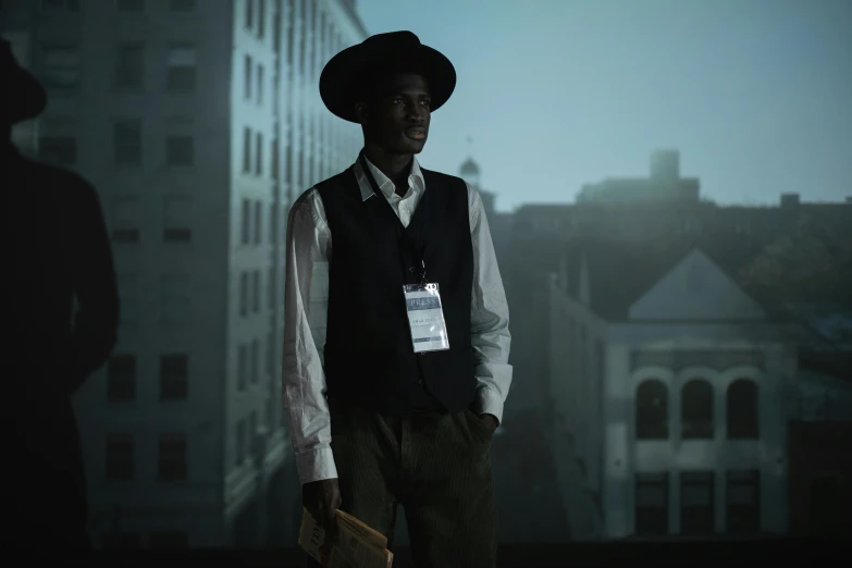 a man in a hat standing in front of a building, inspired by Gordon Parks, adut akech, in dark night, **cinematic, western era