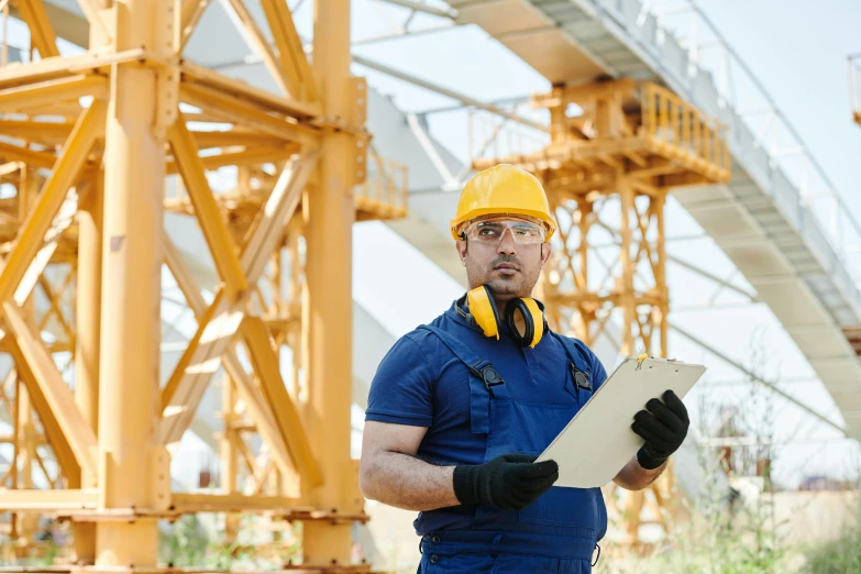 a man in a hard hat holding a clipboard, a portrait, shutterstock, tall metal towers, truss building, yellow overall, thumbnail