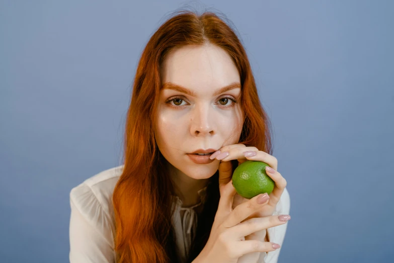 a woman holding a green apple in front of her face, trending on pexels, hyperrealism, ( redhead, 🐿🍸🍋, hand on her chin, 🍸🍋