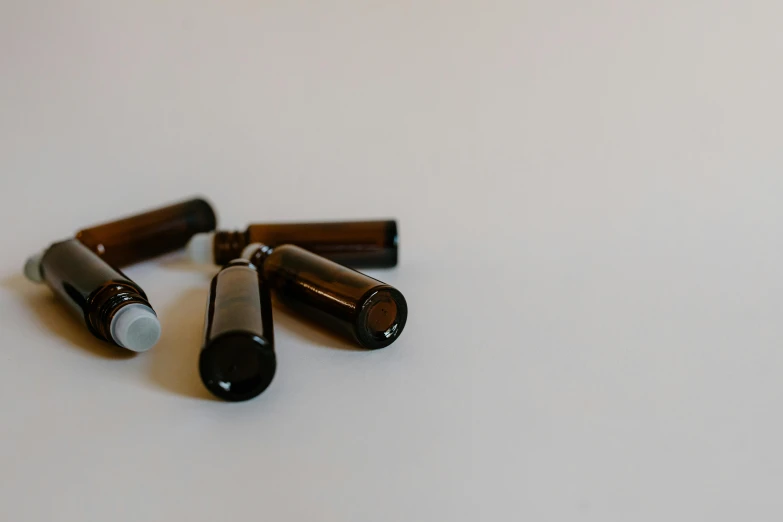 a group of brown bottles sitting on top of a white table, unsplash, healing tubes, ivory and ebony, 3/4 view from below, smoky