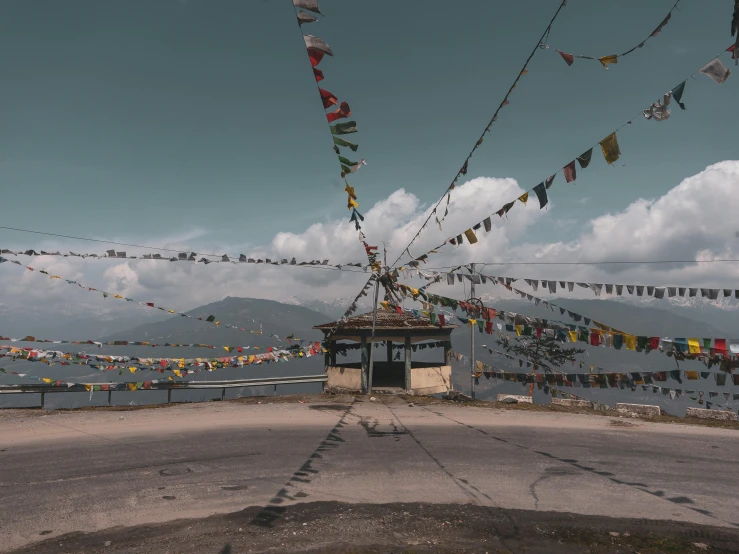 a small building sitting on the side of a road, trending on unsplash, prayer flags, panorama view, fan favorite, dmt temple