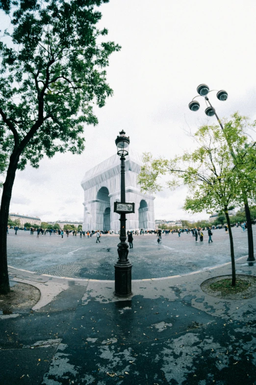 a street filled with lots of traffic next to tall trees, an album cover, inspired by Thomas Struth, unsplash contest winner, renaissance, arc de triomphe full of graffiti, panorama, photo taken on fujifilm superia, town square