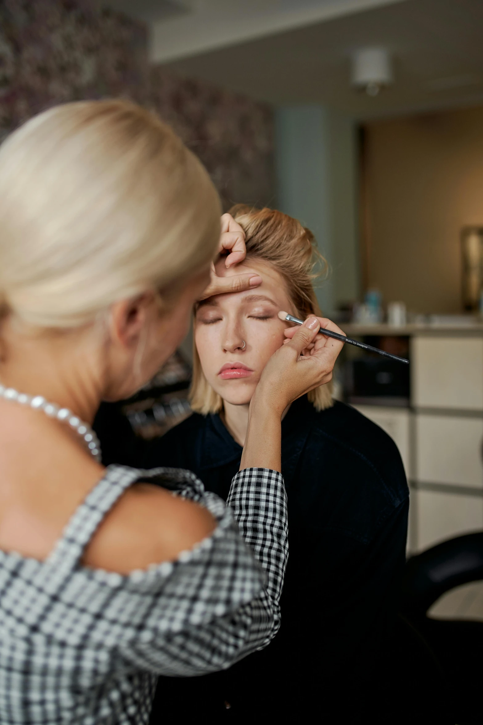 a woman is getting her make up done, by Adam Saks, blonde swedish woman, thumbnail, head down, eyebrows