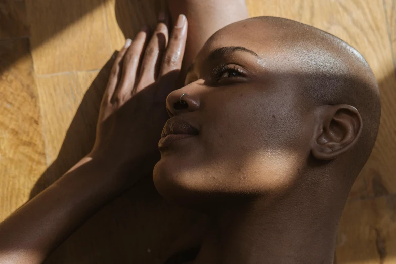 a close up of a person with a bald head, by Lily Delissa Joseph, pexels contest winner, photoshoot for skincare brand, sun overhead, body portrait, maria borges