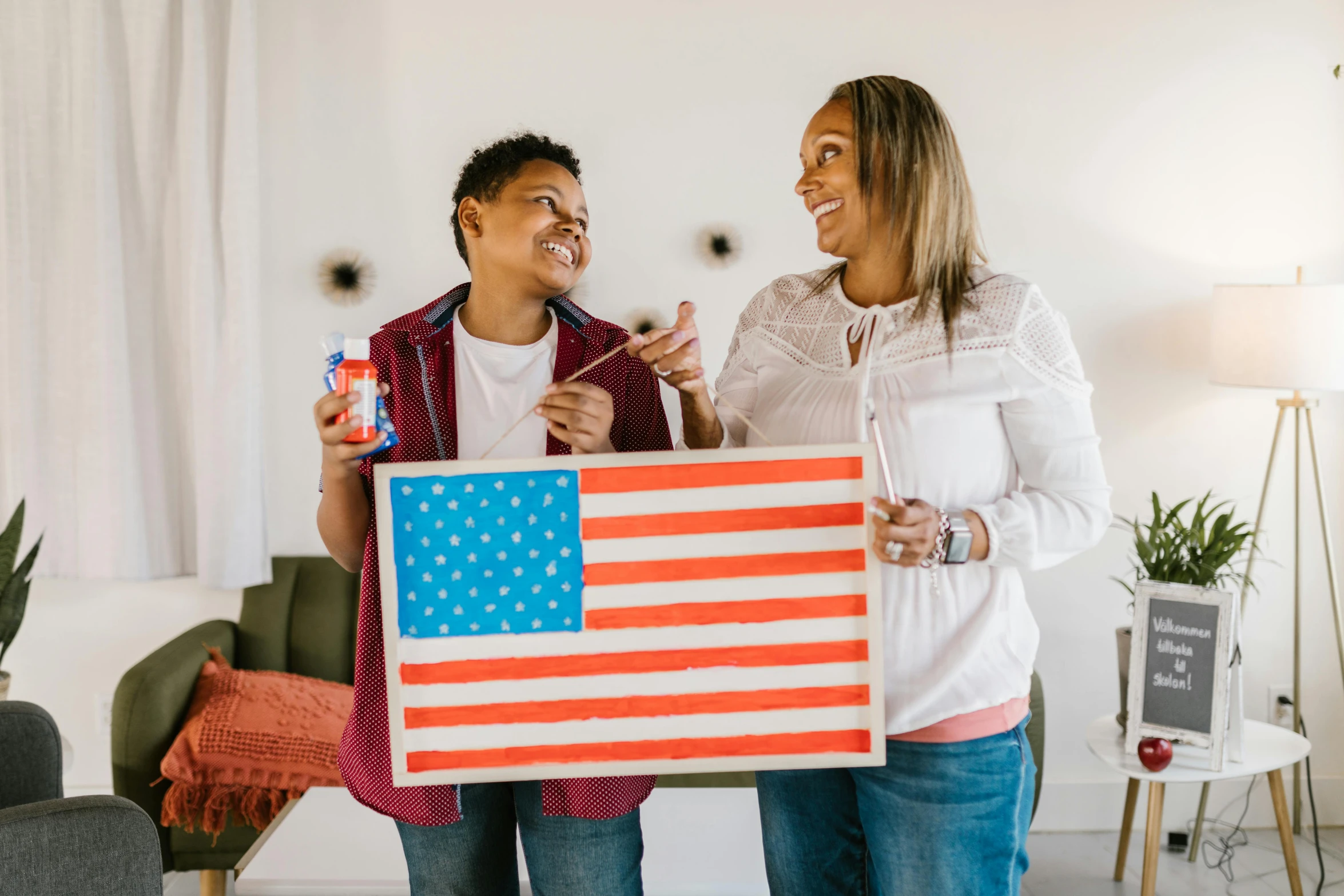 a man and a woman holding an american flag, pexels contest winner, american scene painting, board games on a table, your mom, woman holding sign, kid