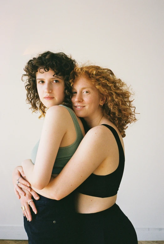 a couple of women standing next to each other, curls on top, holding each other, half male and half female, hila klein