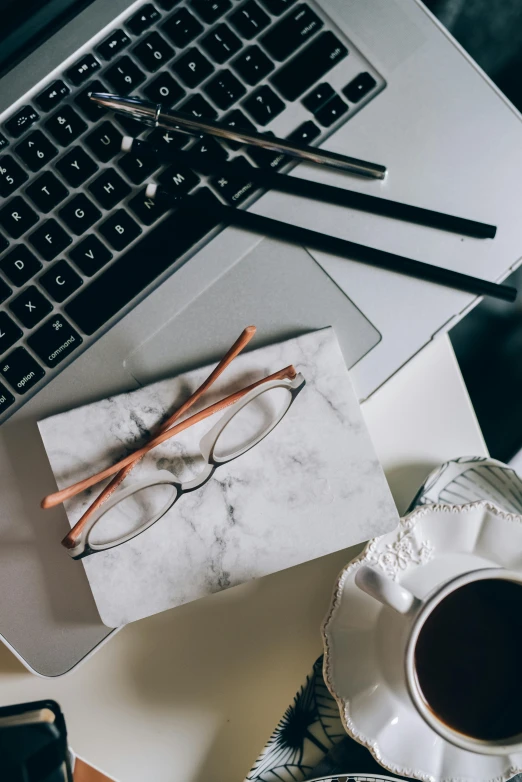 a laptop computer sitting on top of a table next to a cup of coffee, trending on pexels, modernism, white reading glasses, while marble, avatar image, very ornate