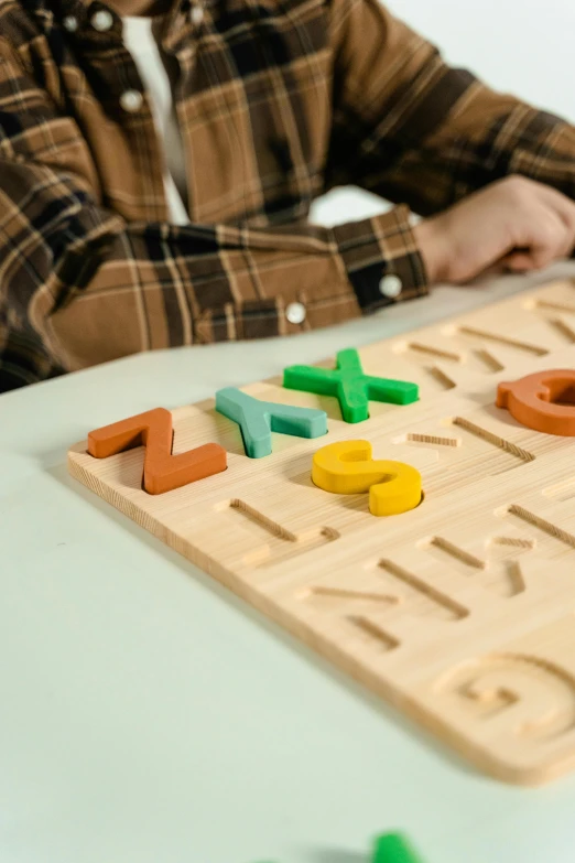 a young boy sitting at a table playing a board game, a jigsaw puzzle, by Julia Pishtar, letterism, pastel colourful 3 d, made of bamboo, product introduction photo, mathematics