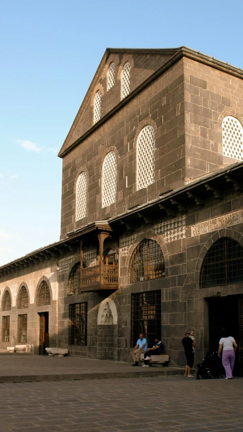 a group of people standing in front of a building, by Afewerk Tekle, pexels contest winner, romanesque, trading depots, damascus, afternoon sunshine, front and side elevation