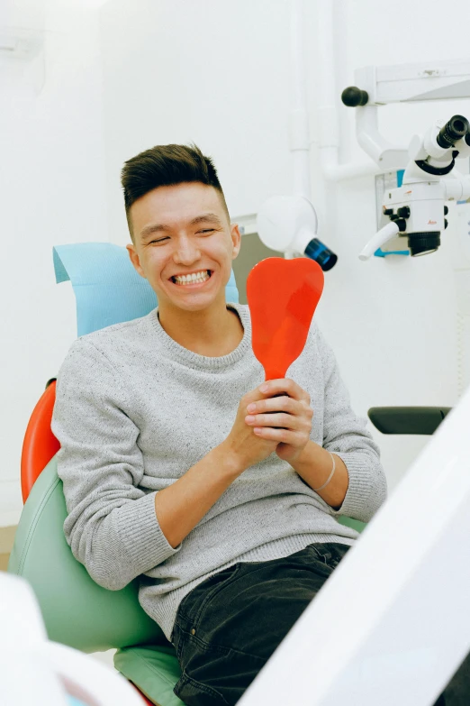 a man smiles while sitting in a dental chair, inspired by Tooth Wu, altermodern, holding a balloon, coloured photo, professional modeling, cast