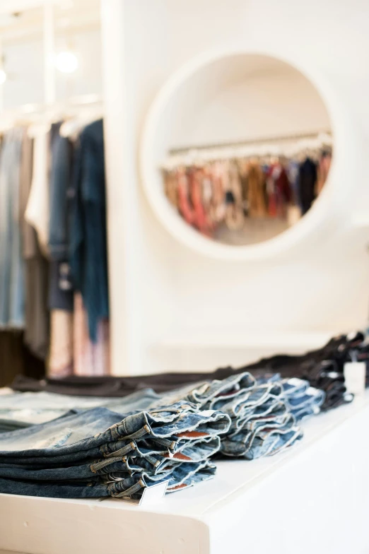 a pile of jeans sitting on top of a white counter, a photo, by Emanuel Witz, happening, the store, coast, loosely cropped, customers