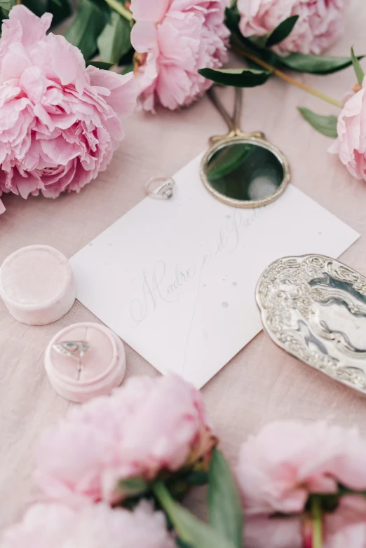 a bunch of pink flowers sitting on top of a table, inspired by Eden Box, trending on unsplash, romanticism, silver details, calligraphy, note detailed, jewels