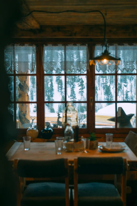 a table and chairs in front of a window, a picture, inspired by Elsa Bleda, pexels contest winner, chalet, chef table, winter, brown