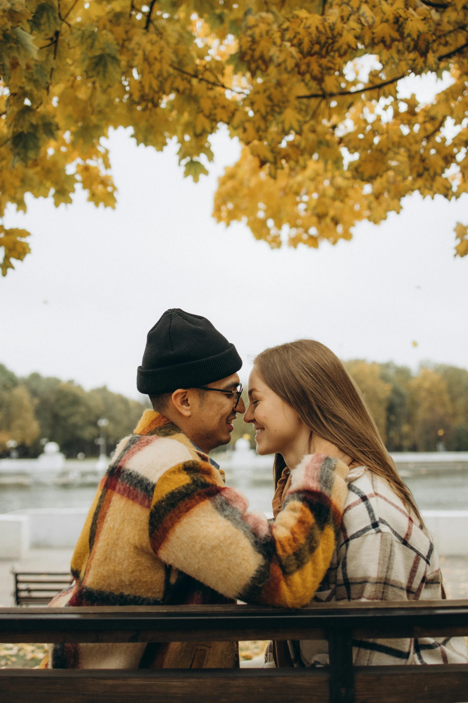 a man and a woman are sitting on a bench, a photo, trending on pexels, lesbian embrace, trees in background, 🍁 cute, helsinki