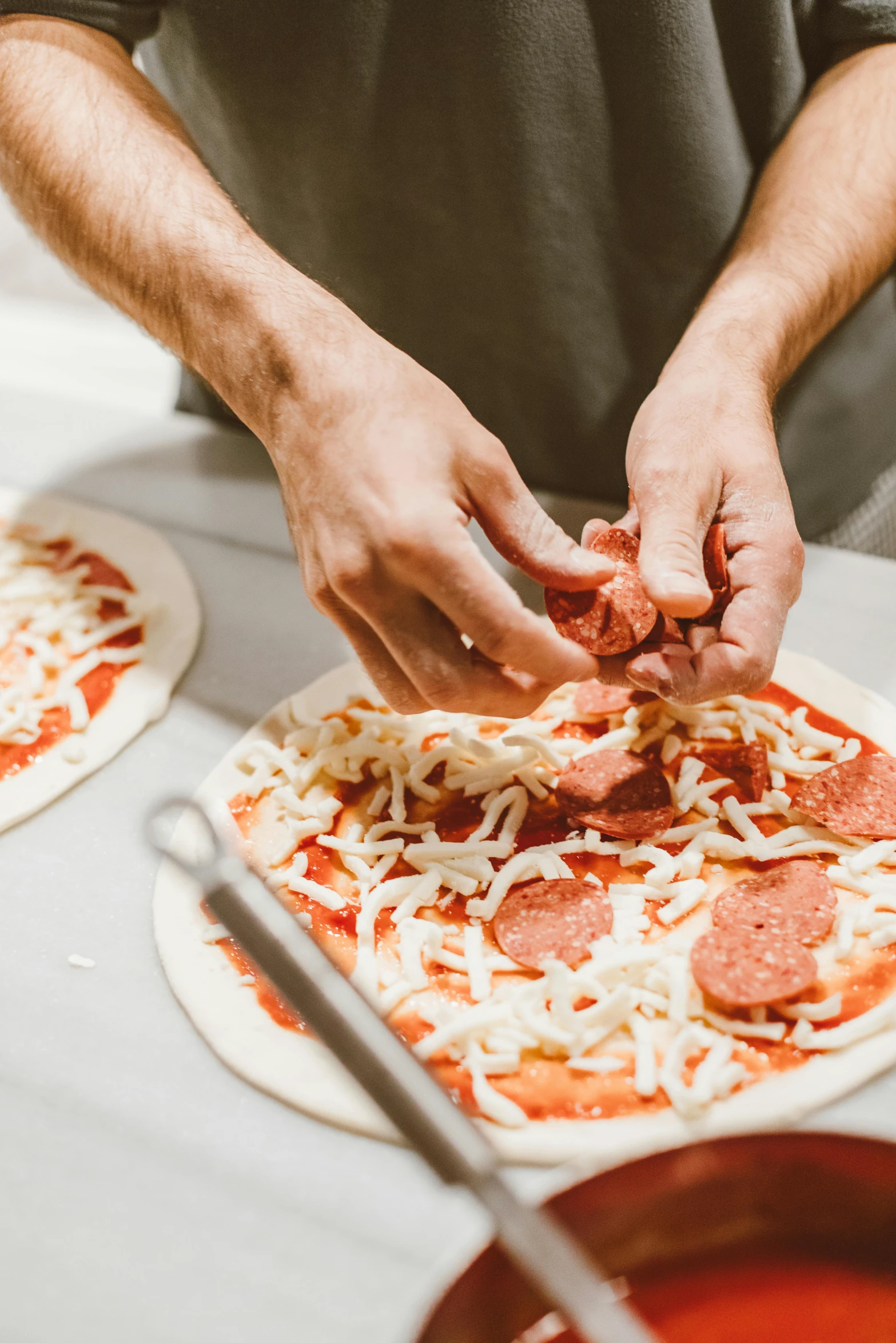 a man making a pizza with pepperoni and cheese, pexels contest winner, curved blades on each hand, splento