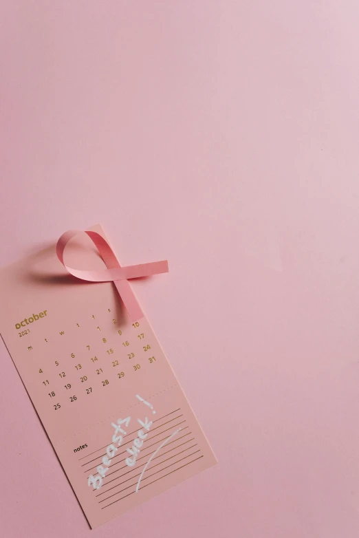 a calendar with a pink ribbon on a pink background, by Julia Pishtar, pexels contest winner, made of silk paper, 15081959 21121991 01012000 4k, diecut, topknot