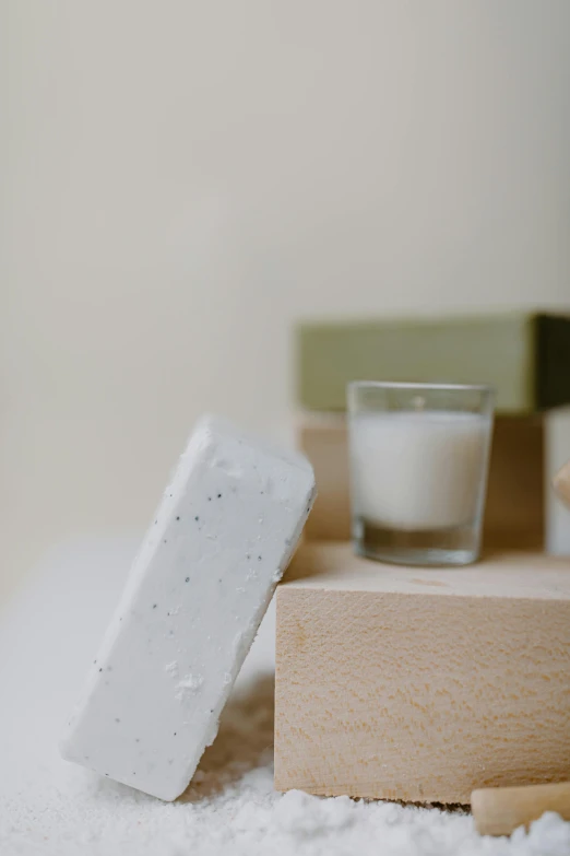 a couple of soap bars sitting on top of a pile of snow, a marble sculpture, inspired by Rachel Whiteread, trending on unsplash, the candle is on a wooden table, table in front with a cup, muted green, set against a white background