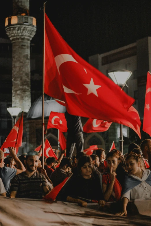 a crowd of people holding flags in front of a building, a colorized photo, pexels contest winner, hurufiyya, turkey, avatar image, summer night, square