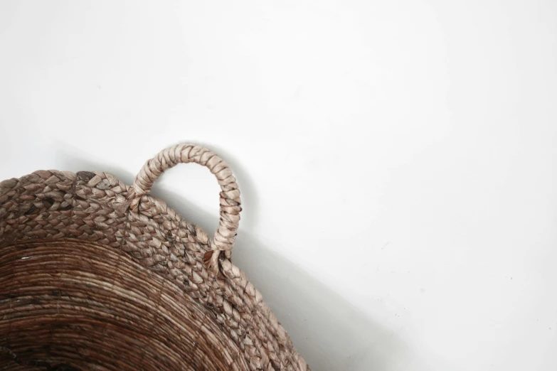 a close up of a basket hanging on a wall, inspired by Jakob Emanuel Handmann, trending on pexels, mingei, with a white background, detailed close foot shot, brown, product shot