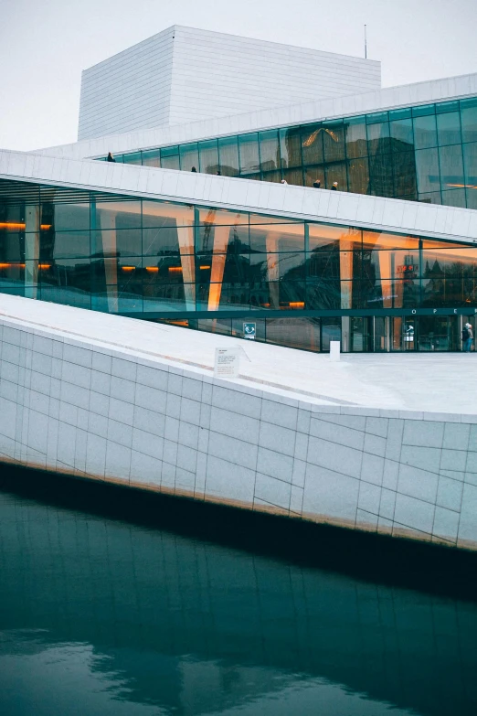 a building that is next to a body of water, by Sven Nordqvist, trending on unsplash, modernism, concert hall, lots of glass details, thumbnail, viking palace