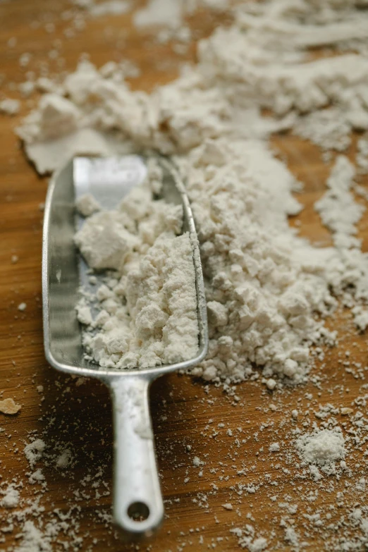 a scoop of flour sitting on top of a wooden table, cocaine, crust, detailed product image, epicurious