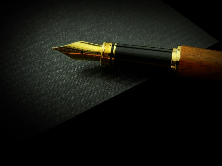 a fountain pen sitting on top of a piece of paper, pexels contest winner, photorealism, with a black background, gold, brown, thumbnail