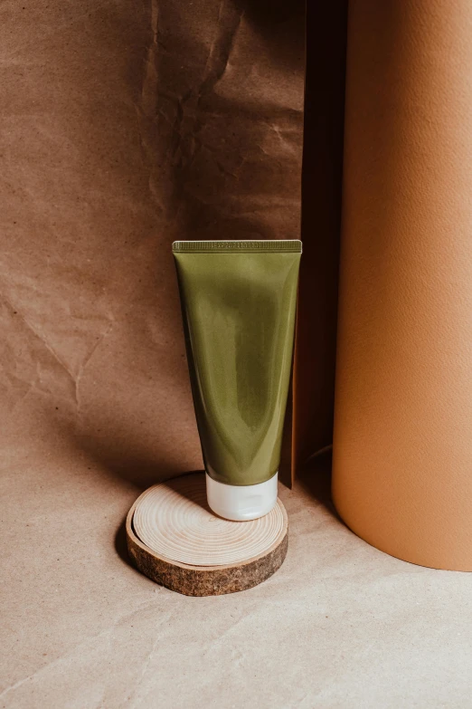 a tube of toothpaste next to a bottle of toothpaste, by Andries Stock, trending on pexels, art nouveau, lush greens, handcrafted paper background, brown mud, photoshoot for skincare brand