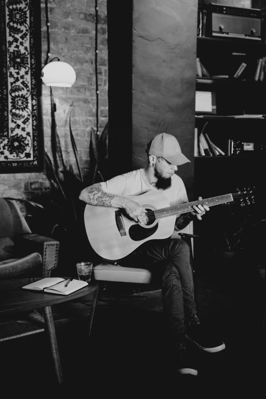 a man sitting in a chair playing a guitar, a black and white photo, by Jeremy Henderson, pexels contest winner, mac miller, sitting on a mocha-colored table, illustration:.4, profile picture