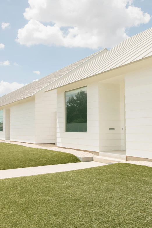 a white house sitting on top of a lush green field, inspired by Agnes Martin, exterior, units, kailee mandel, neotraditional modern