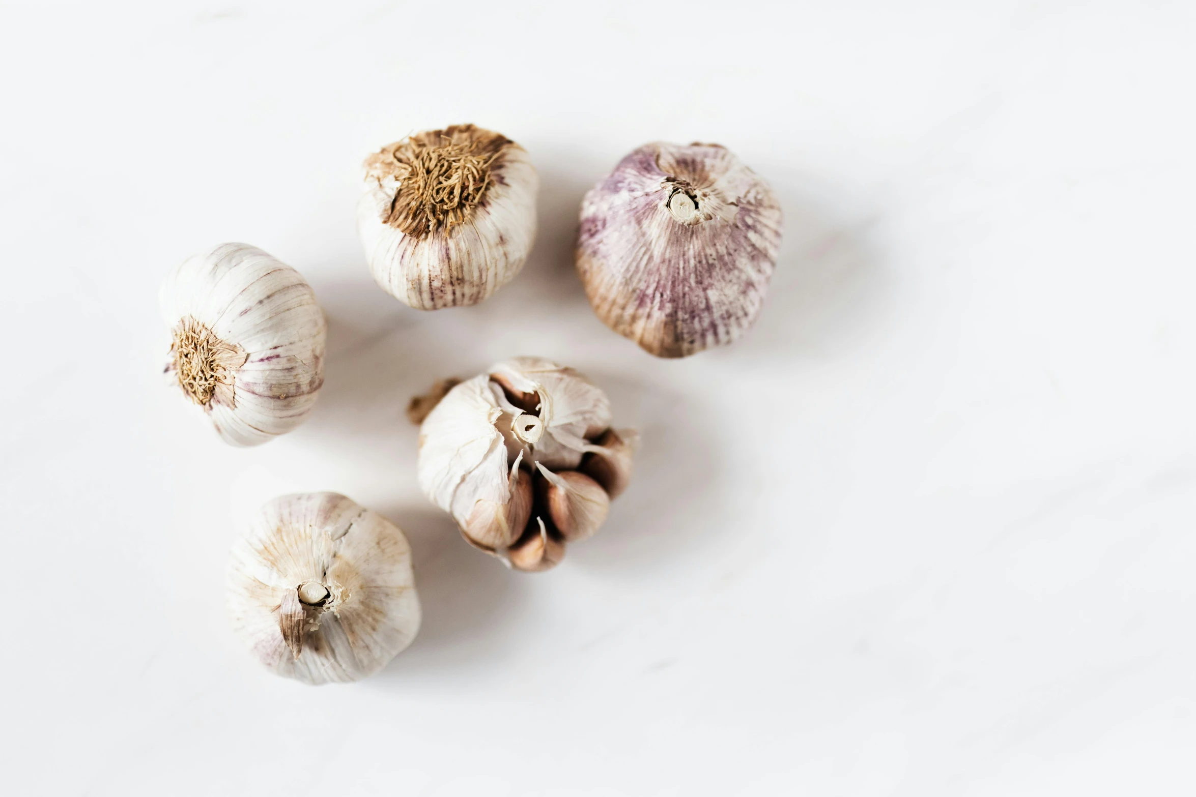 several cloves of garlic on a white surface, by Carey Morris, trending on unsplash, fan favorite, all marble, 6 pack, multicoloured