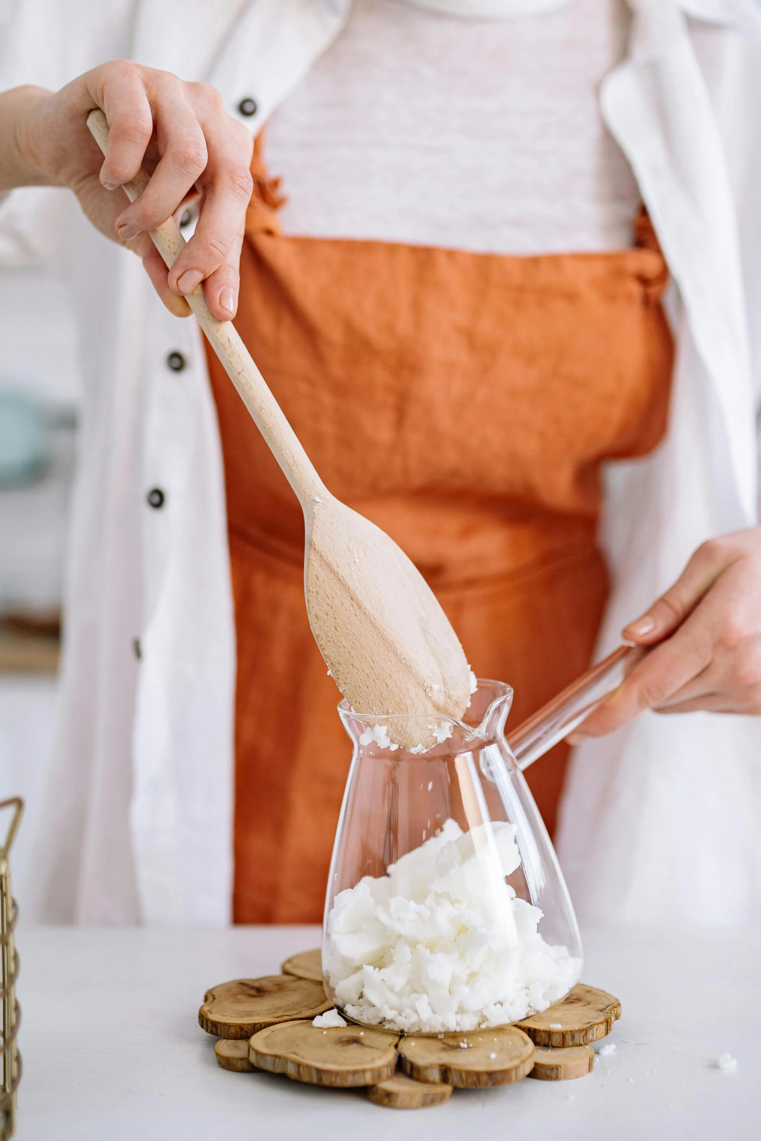 a woman in an orange apron holding a wooden spoon, trending on pexels, process art, whipped cream on top, glassware, cone shaped, white