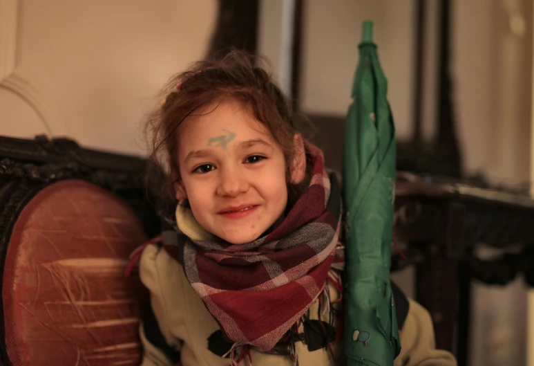 a little girl sitting on a chair holding an umbrella, a portrait, pexels contest winner, hurufiyya, markings on his face, rojava, holding a rocket, #green