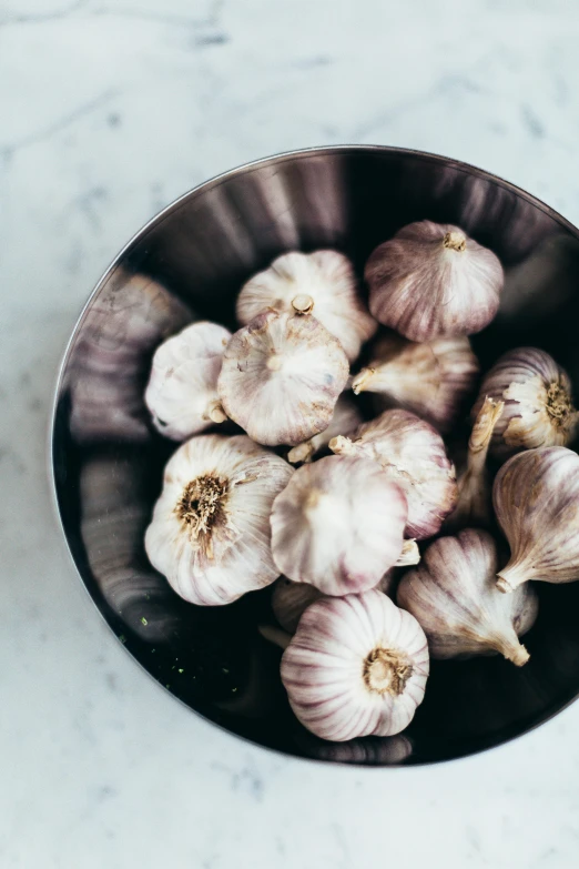 a bowl filled with garlic on top of a table, by Carey Morris, trending on unsplash, renaissance, silver haired, epicurious, lulu chen, full frame image