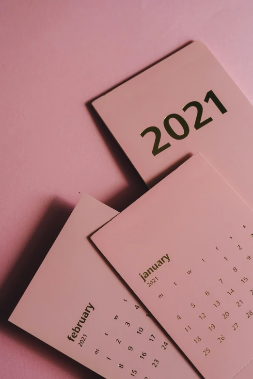 a calendar sitting on top of a pink surface, by Carey Morris, trending on pexels, contest winner 2021, thumbnail, cardboard, set photo