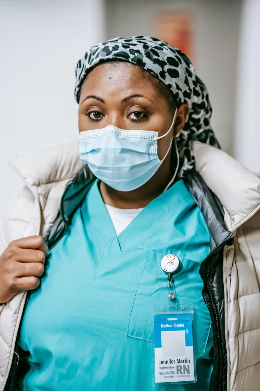 a woman wearing a blue scrub suit and a face mask, a picture, by Arabella Rankin, trending on pexels, somali woman, nurse costume, plus-sized, center of image