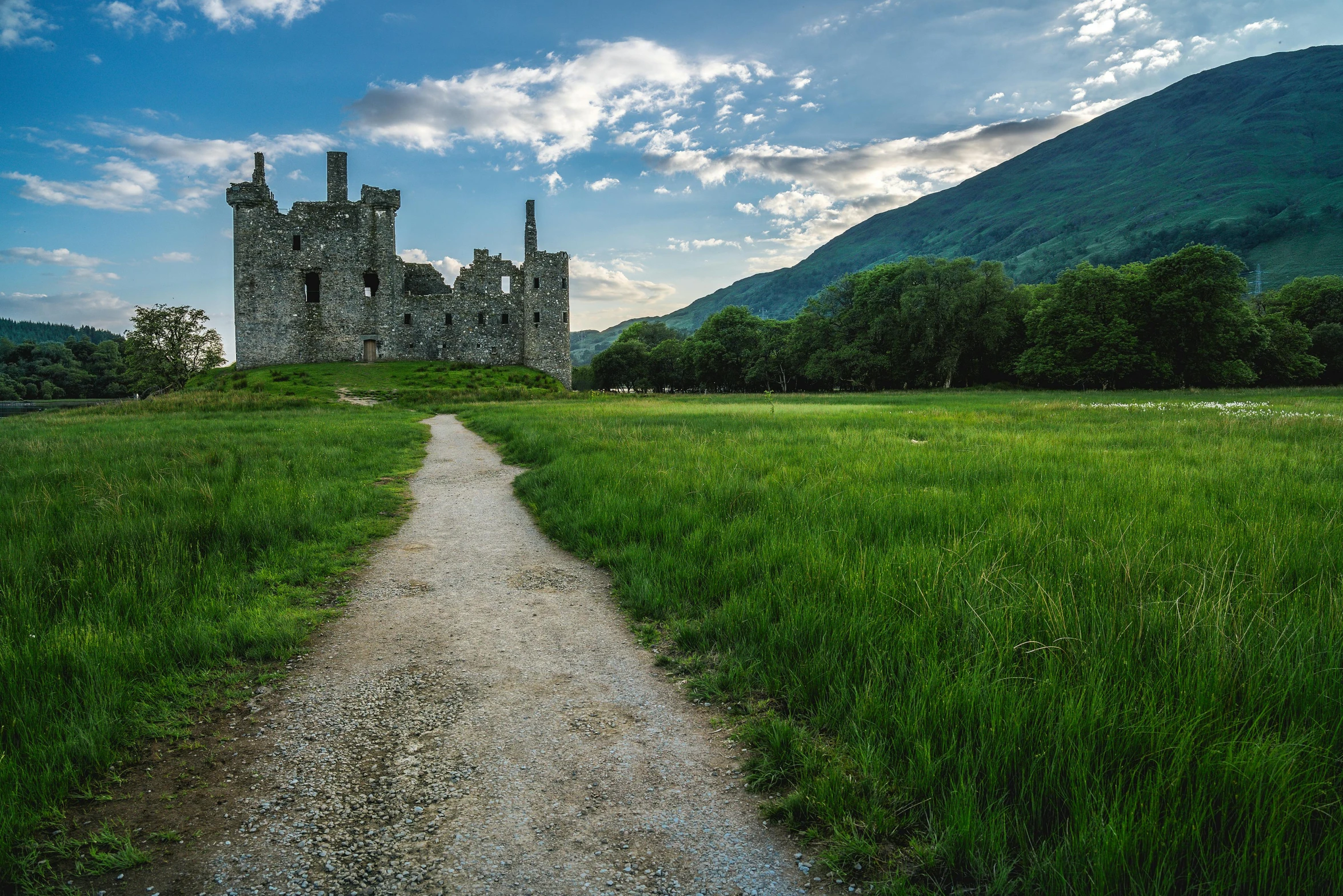 a castle sitting on top of a lush green field, by Andrew Allan, unsplash contest winner, natural stone road, land of ruins, highlands, conde nast traveler photo