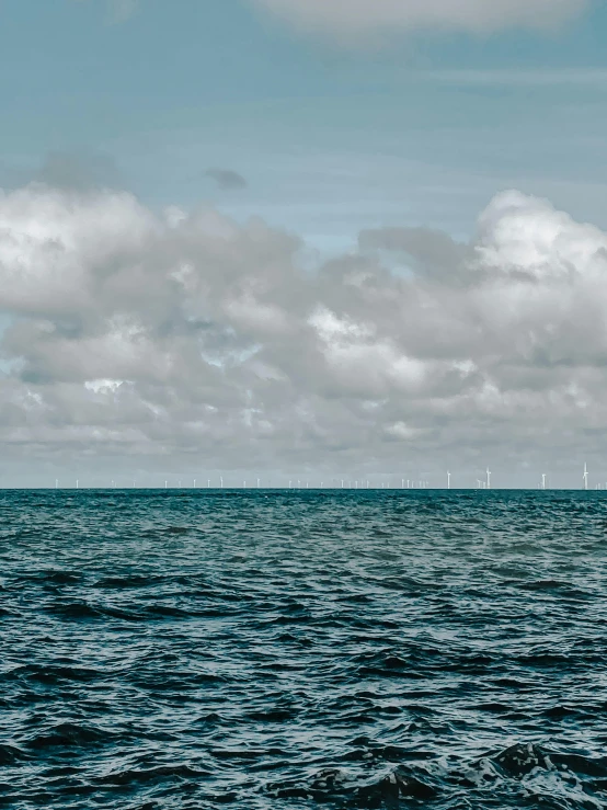a sailboat in the middle of a large body of water, a picture, by Jan Tengnagel, pexels contest winner, turbines, clouds and waves, low quality photo, screensaver