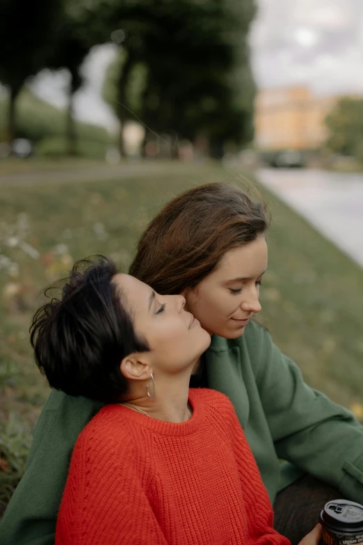 a couple of women sitting next to each other, a picture, by Attila Meszlenyi, trending on pexels, lesbian embrace, park in background, 15081959 21121991 01012000 4k, medium head to shoulder shot