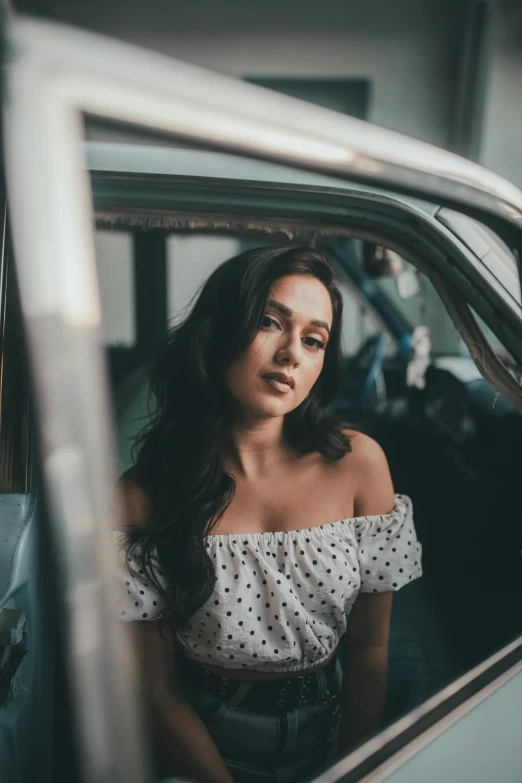 a woman sitting in a car looking out the window, pexels contest winner, female camila mendes, square, sultry, polka dot